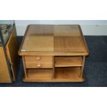 An Ercol Coffee Table, square form, with shelves and drawers, raised on casters, with glass top.