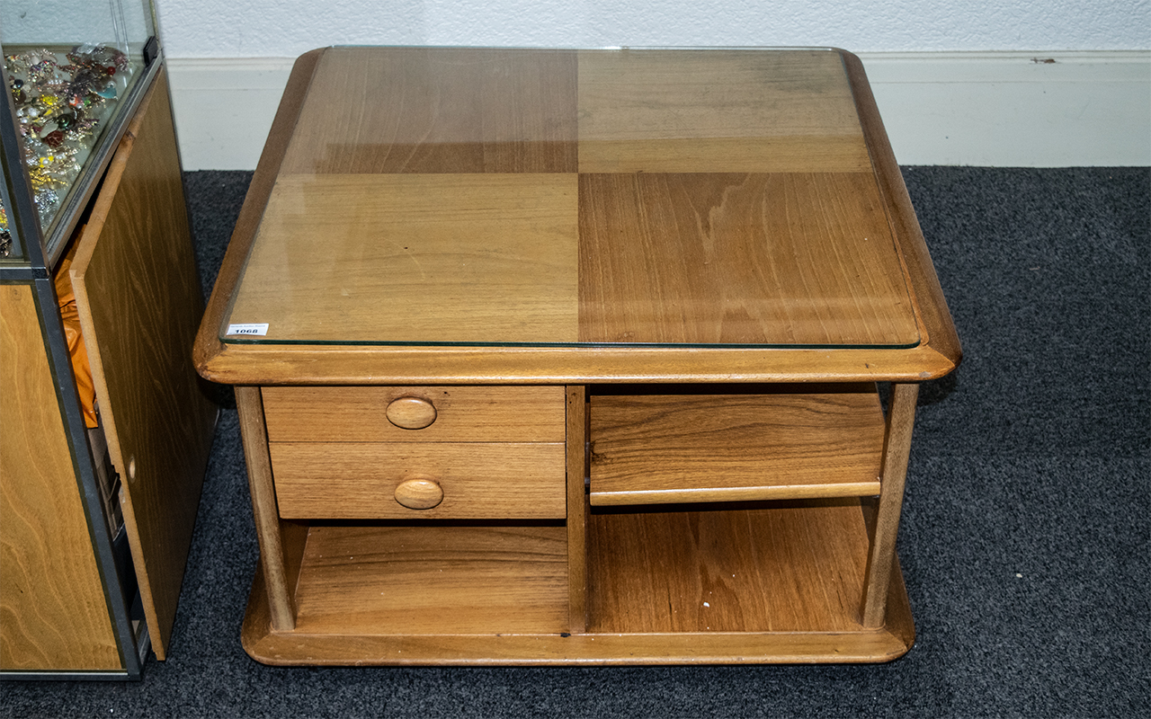 An Ercol Coffee Table, square form, with shelves and drawers, raised on casters, with glass top. - Image 2 of 3