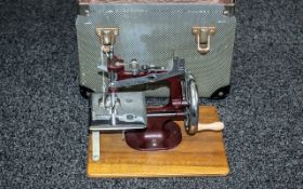 Mid 20th Century Child's Miniature Sewing Machine, in chrome with burgundy enamel frame.