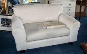 Two Seater Contemporary Overstuffed Sofa, covered in an ivory coloured material, on square feet.