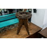 An Indian Carved Wooden Table, the top with raised stylised dragons, on four carved legs.