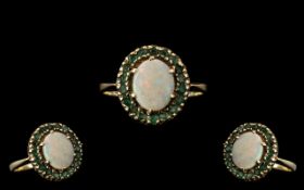 A 9ct Gold Dress Ring Set with Central Opal surrounded by round cut emeralds, fully hallmarked.