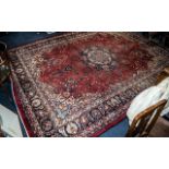 A Genuine Excellent Quality Persian Carpet/Rug decorated in a floral design on a rich red ground.