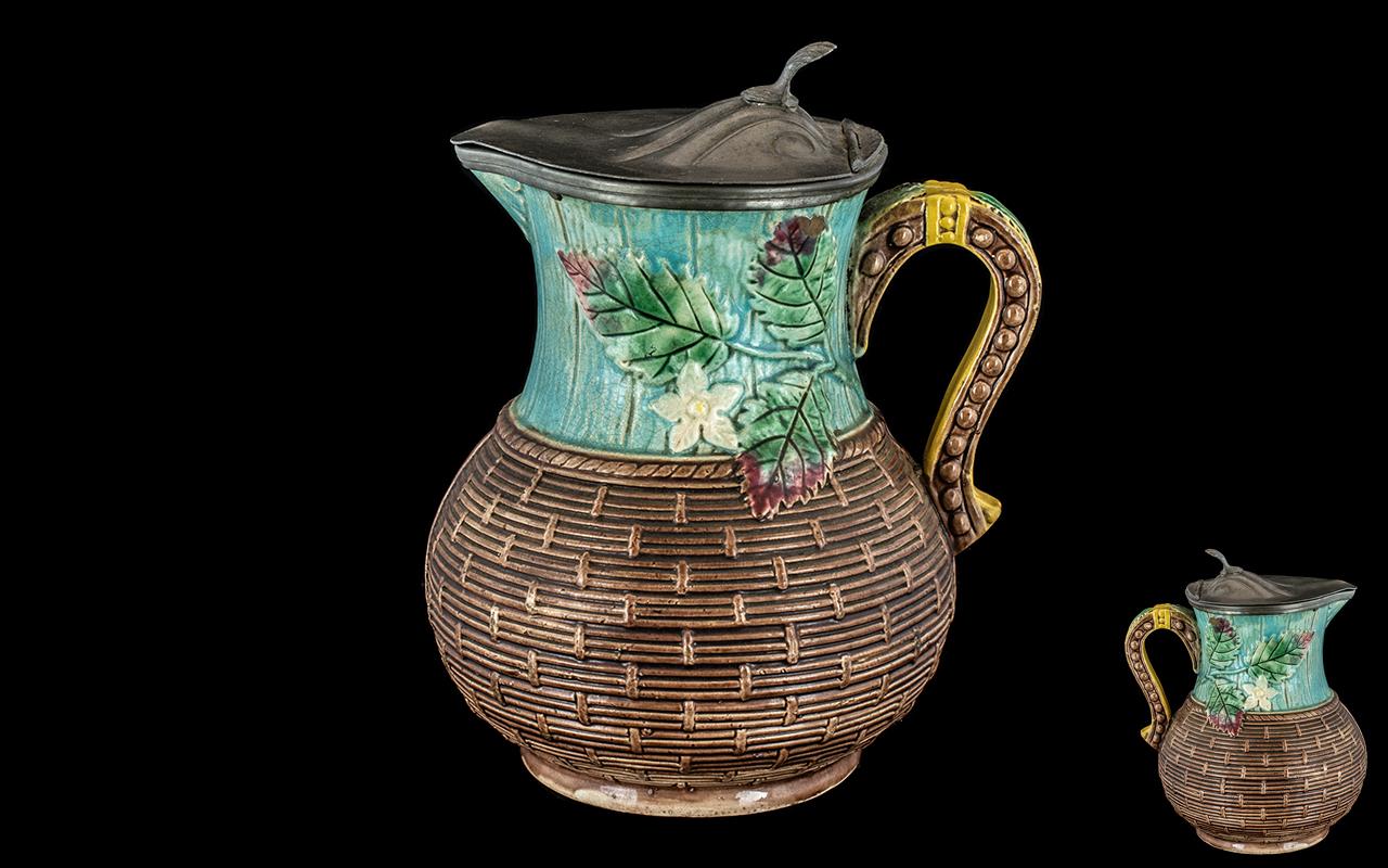 A Continental Majolica Jug, basket weave and leaf design with pewter lid, unmarked. Height 8''.