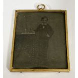 An unusual tintype photograph of a boy standing by a table, circa 1860 and in original brass frame,