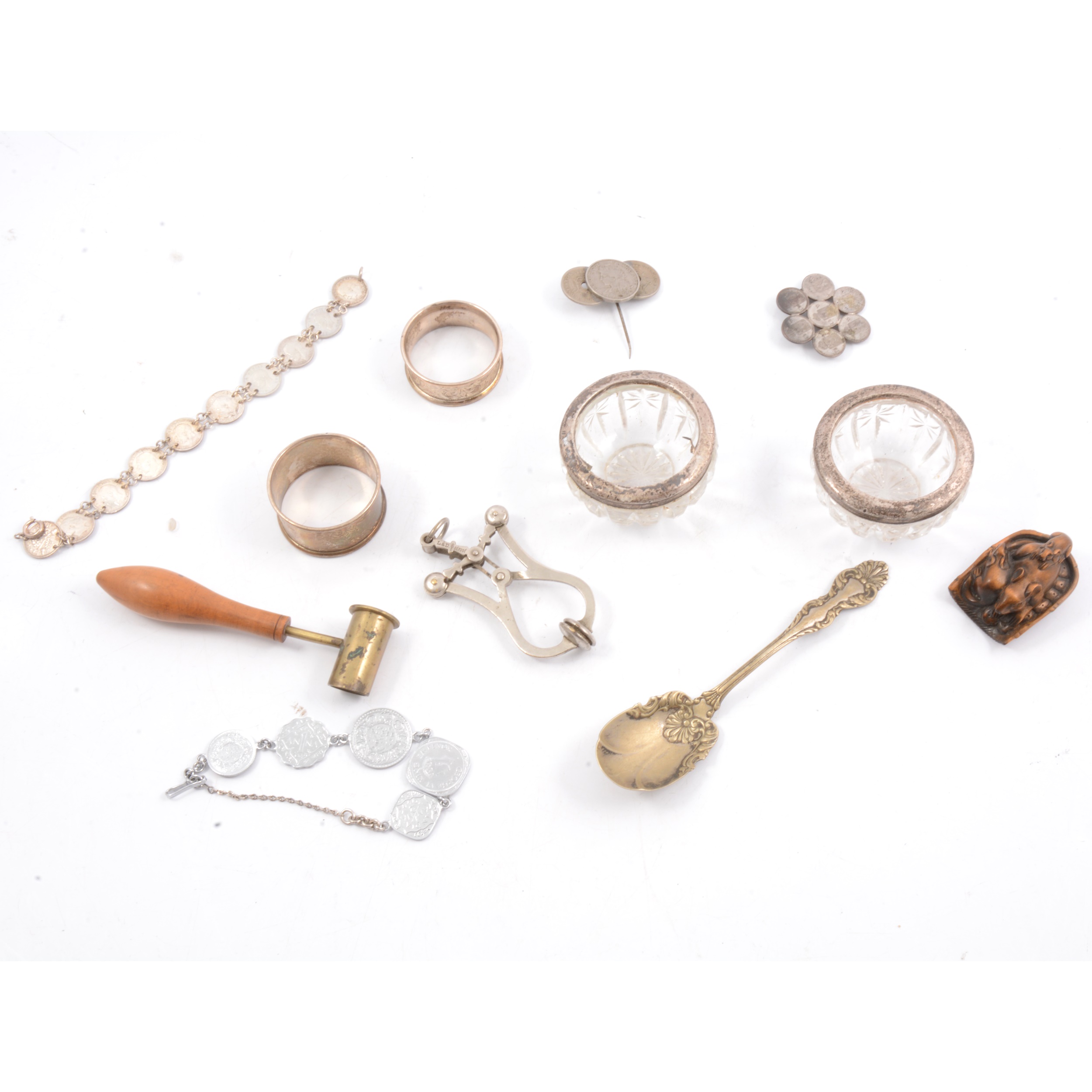 Silver napkin rings, French skirt lifter, netsuke, powder measure, coin jewellery.