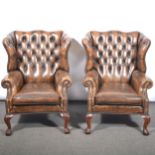 Pair of brown leather and close-studded wing-back easychairs.