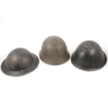 Three military tin helmets,