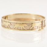 A yellow and white metal bangle marked 375, lion motifs.