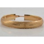 A yellow metal bangle marked 14K.