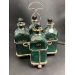 A set of four Victorian cut green glass spirit bottles, in a plated frame, 28cm, three with gilt