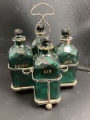 A set of four Victorian cut green glass spirit bottles, in a plated frame, 28cm, three with gilt