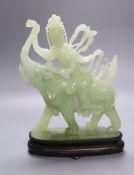 A Chinese bowenite jade group of Guanyin riding on elephant, 27cm high, wood stand