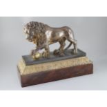 An early 19th century cast iron model of a lion standing with it's foot upon a brass ball, on marble