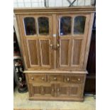 An early 19th century stripped pine cupboard, fitted with a pair of part glazed panelled doors, over
