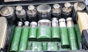 An Edwardian morocco dressing case containing French white metal mounted toilet fitments and a green