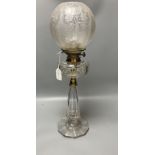 A late 19th century cut glass oil lamp with floral embossed shade, 61cm high including shade