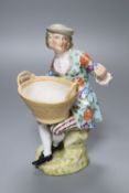 A Sitzendorf porcelain figure of a youth holding a basket, after a Meissen original by J.J.