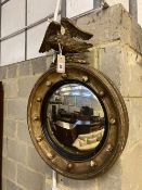 A Regency carved giltwood and gesso circular convex wall mirror with eagle pediment, height 69cm,