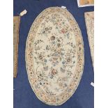 An Antique oval chain-stitch panel centred with flowers in a basket on a cream ground, 151 x 88cm