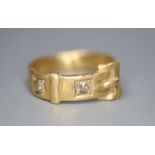 An early 20th century 18ct? gold and two stone diamond set buckle ring, size I, gross 4.1 grams.