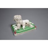 A Staffordshire porcelain group of a poodle and three puppies on a green cushion, c.1835-50, 9cm