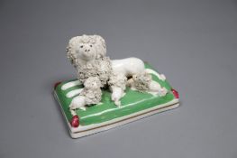A Staffordshire porcelain group of a poodle and three puppies on a green cushion, c.1835-50, 9cm