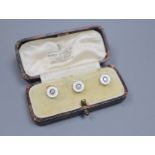 A cased set of three early 20th century yellow metal, mother of pearl and diamond set dress studs,