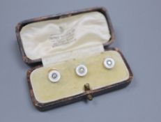 A cased set of three early 20th century yellow metal, mother of pearl and diamond set dress studs,