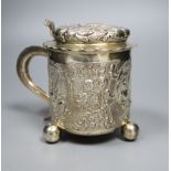 A late 19th century German? silver Scandinavian style embossed lidded tankard, on three ball feet,