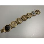 A late Victorian gilt metal bracelet set with seven oval lava plaques carved with busts of ladies,