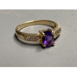 A modern yellow metal, amethyst ring with white stone (possibly white sapphire) set shoulders,