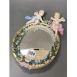 A 19th century Meissen porcelain framed oval mirror surmounted with two angelic figures, height