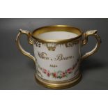 An English porcelain two handled mug lavishly painted with flowers, inscribed verso William Brown