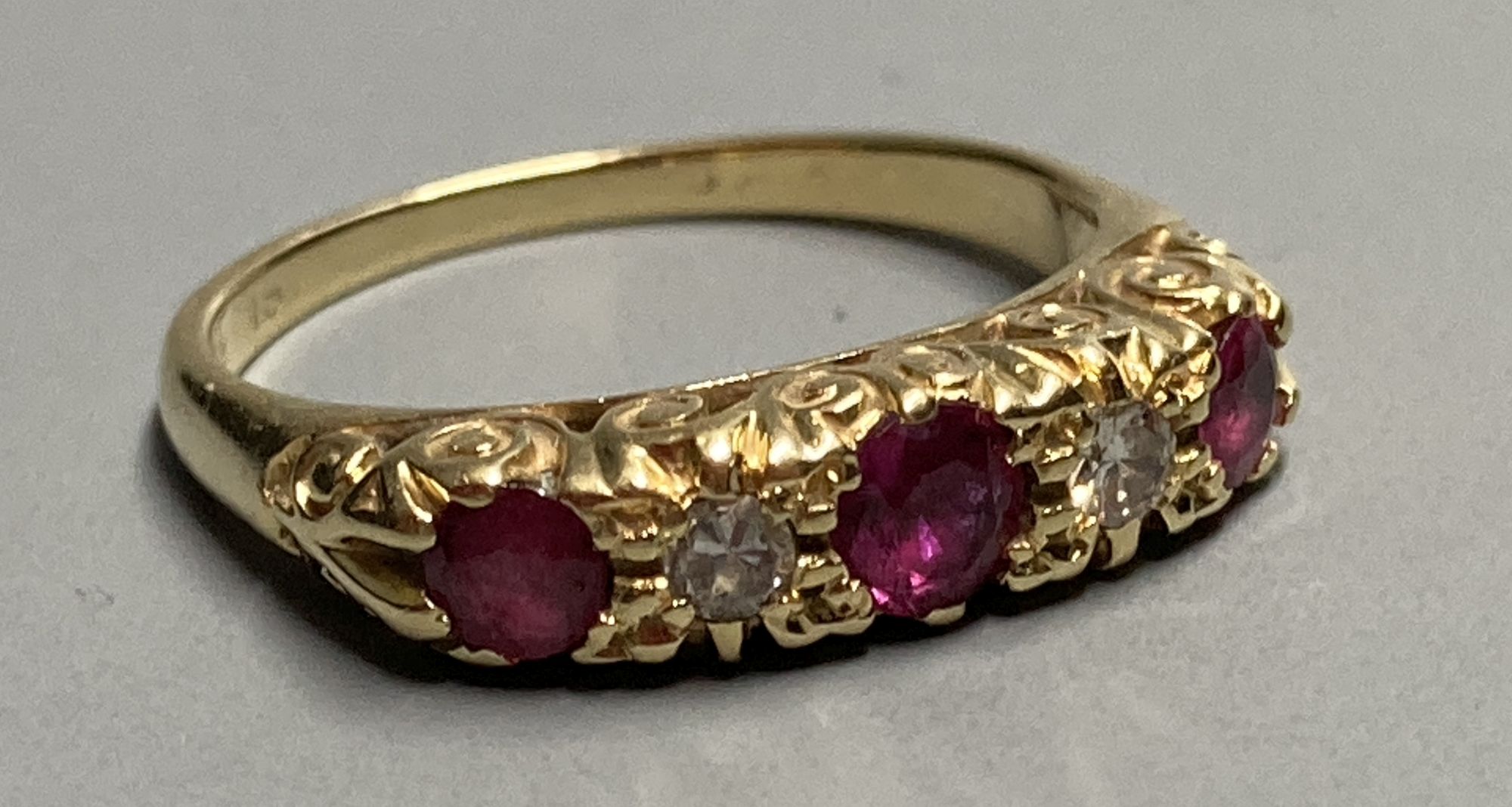 An 18ct Victorian style two stone diamond and three stone ruby set half hoop ring, size K/L. gross