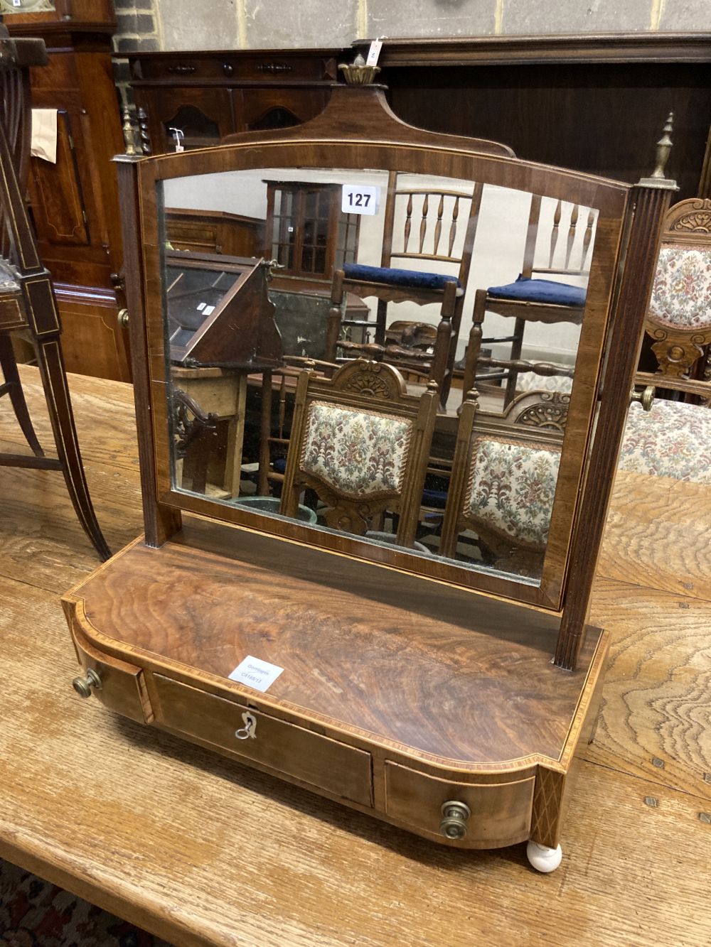 A George III mahogany and tulipwood banded bowfronted toilet mirror, on ivory ball feet, width