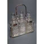 An Edwardian plated decanter stand, fitted three square cut glass decanters and three silver