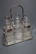 An Edwardian plated decanter stand, fitted three square cut glass decanters and three silver