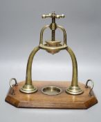 An Edwardian brass lemon squeezer on an oak plinth