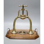 An Edwardian brass lemon squeezer on an oak plinth