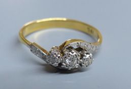 An 18ct and illusion set three stone diamond crossover ring, size R, gross 3.2 grams.CONDITION: