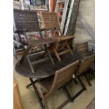 A weathered teak garden table and six teak folding chairs (two with arms)