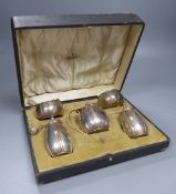A cased George V silver five piece condiment set with two matching spoons, Walker & Hall, Sheffield,