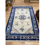 A Chinese wool cream ground rug, centred by a blue and pink medallion surrounded by vases of