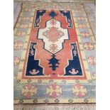 An Afghan Kazak rug, the red and blue ground field centred by an ivory cruciform medallion, woven
