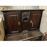 An 18th century style carved oak two door wall cabinet, with concealed central compartment, width
