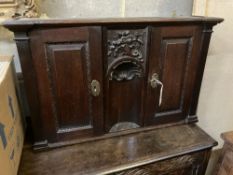 An 18th century style carved oak two door wall cabinet, with concealed central compartment, width