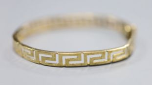 A 9ct gold Greek key design hinged bangle, 10g.CONDITION: A little misshapen near the clasp.