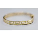 A 9ct gold Greek key design hinged bangle, 10g.CONDITION: A little misshapen near the clasp.