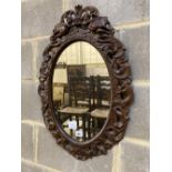 A Carolean style carved walnut oval mirror, width 48cm, height 68cm